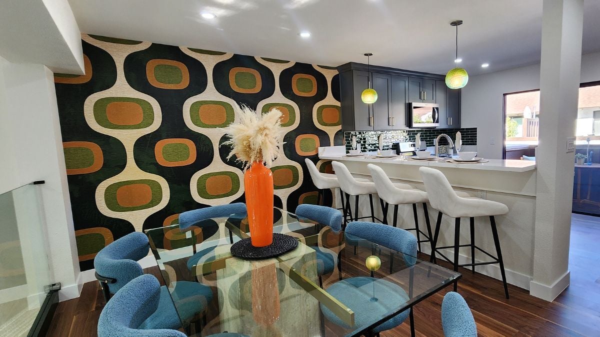 Mid-century inspired dining and kitchen area with bold wallpaper and modern lighting